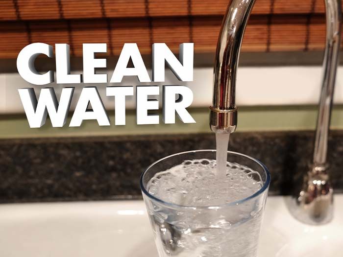 glass of water filling up in the sink with the words "clean water"