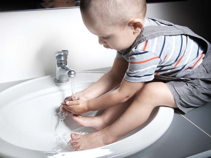 young child playing in the sink