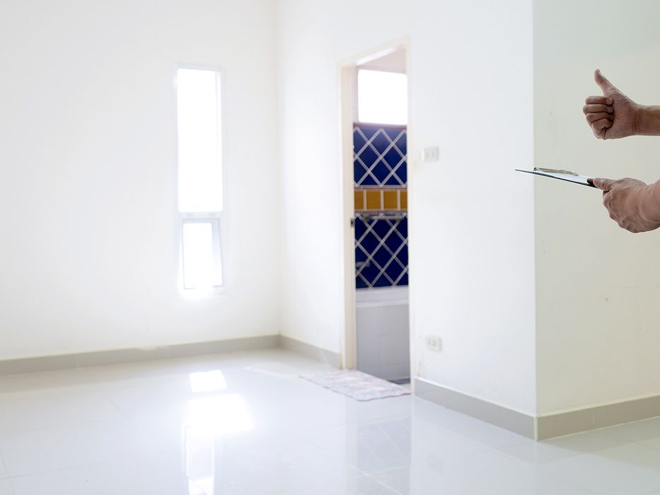 Man holding a clipboard giving a “thumbs up” in an an empty living room.