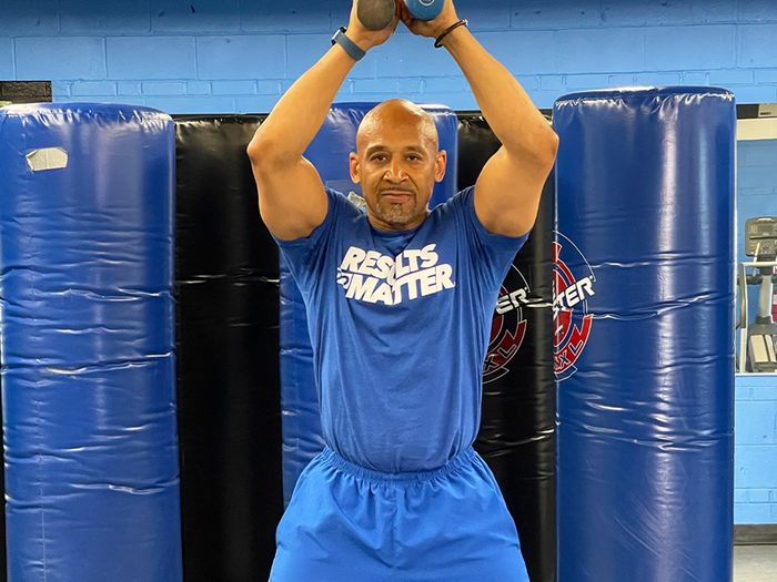 B.O.S.S. Fitness trainer holding dumbbells above his head