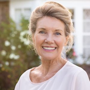 A smiling senior woman with blonde hair, looking directly at the camera with a bright, confident smile, outdoors in soft focus. A smiling senior woman with blonde hair, looking directly at the camera with a bright, confident smile, outdoors in soft focus.