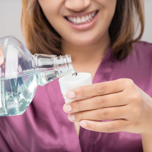 A woman using mouthwash.