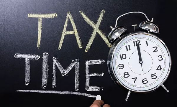 Image of clock and writing on a chalk board that says Tax Time.