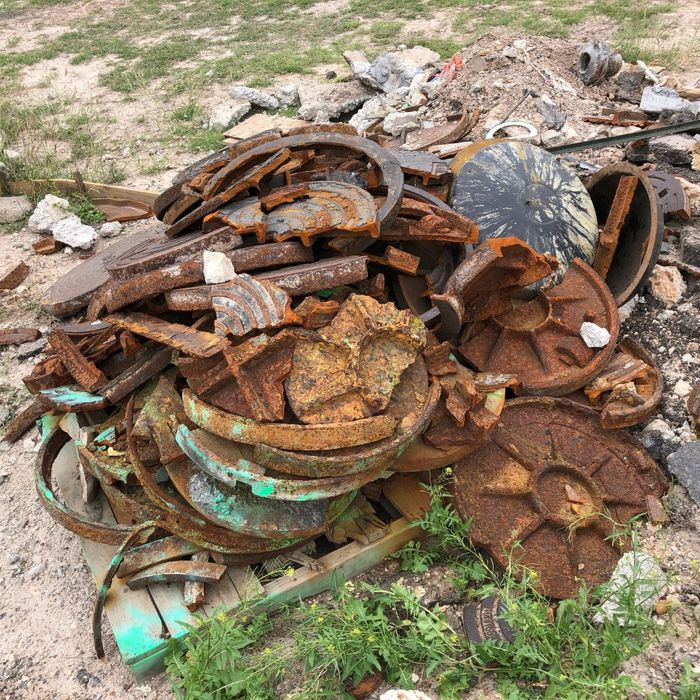 a pile of corroded iron manhole covers