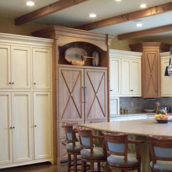 Kitchen with white cabinets and wood toned cabinets over the fridge