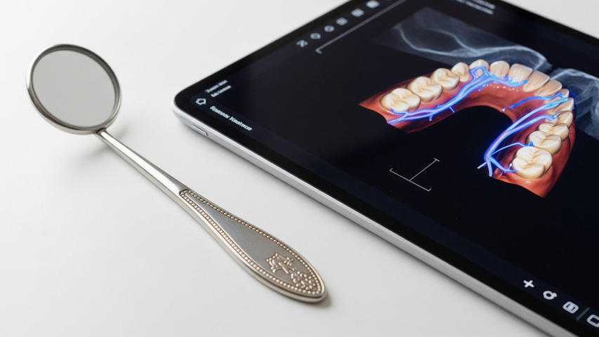 A vintage dental instrument beside a modern tablet displaying a 3D scan, symbolizing 40 years of dental evolution