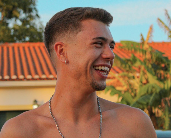 A young man with a joyful, natural laugh and a healthy smile enjoys a sunny day outdoors.