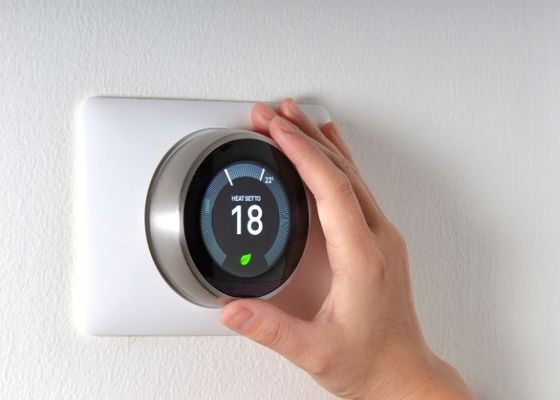 person adjusting a thermostat.