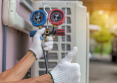 HVAC technician holding a manifold gauge set and giving a thumbs up.