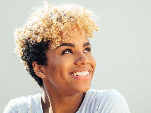 African American woman with blonde, curly hair, smiling.