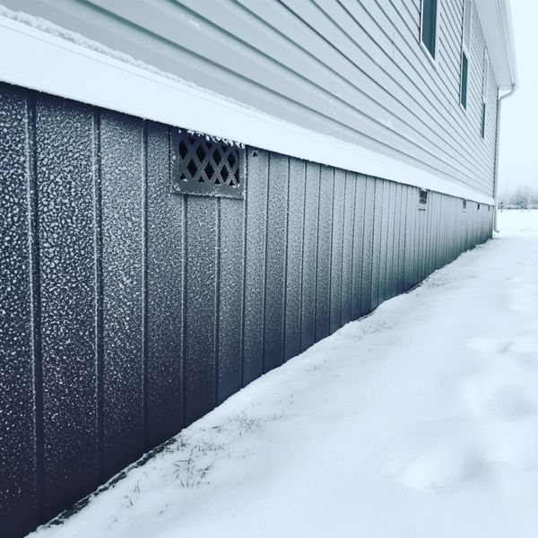 Crawl space and skirting of a prefabricated home with light snow