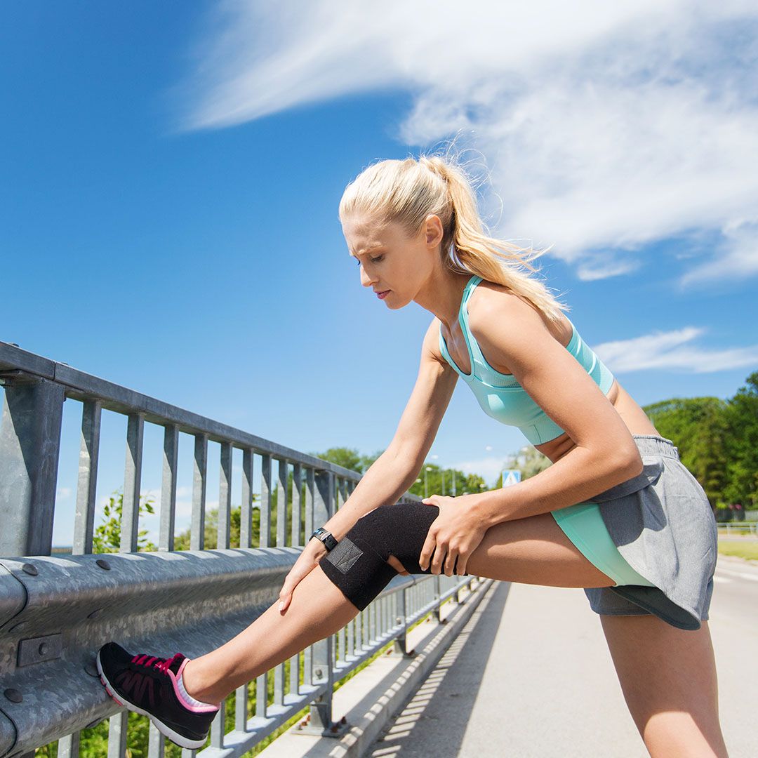 woman warming up knee with brace on it before a run
