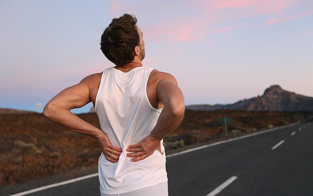 Man outdoors with his hands on his back