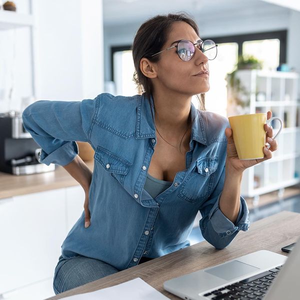 Woman sitting at a desk with her hand on her back