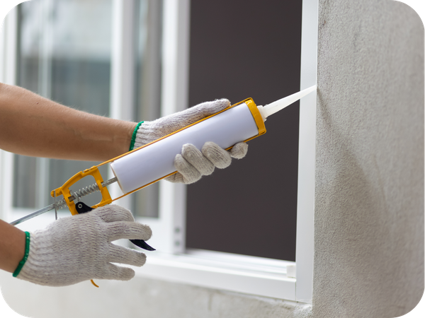 Contractor applying caulking to outside of a window for waterproofing. roofing waterproofing.png