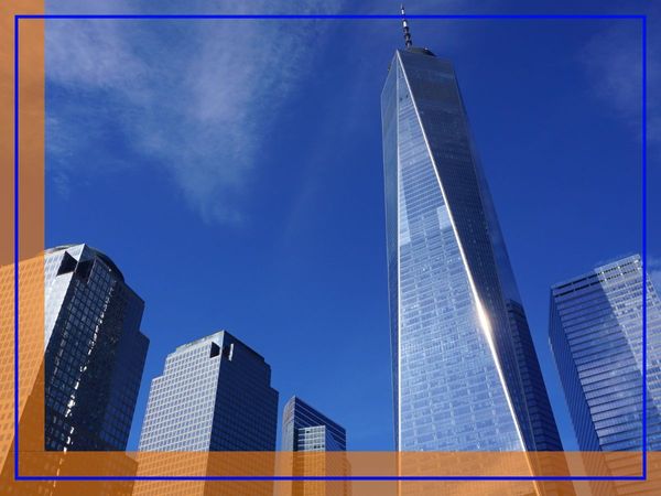 A low-angle view of modern glass skyscrapers in Manhattan against a bright blue sky. A low-angle view of modern glass skyscrapers in Manhattan against a bright blue sky.