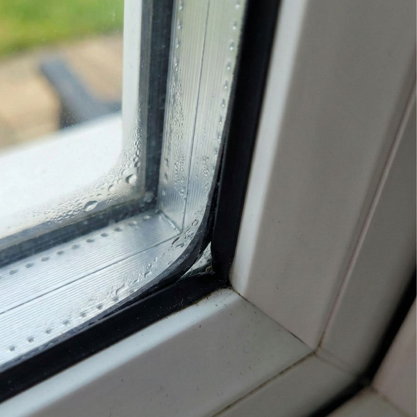 A close-up view of a failed window seal with visible moisture inside the glass unit.