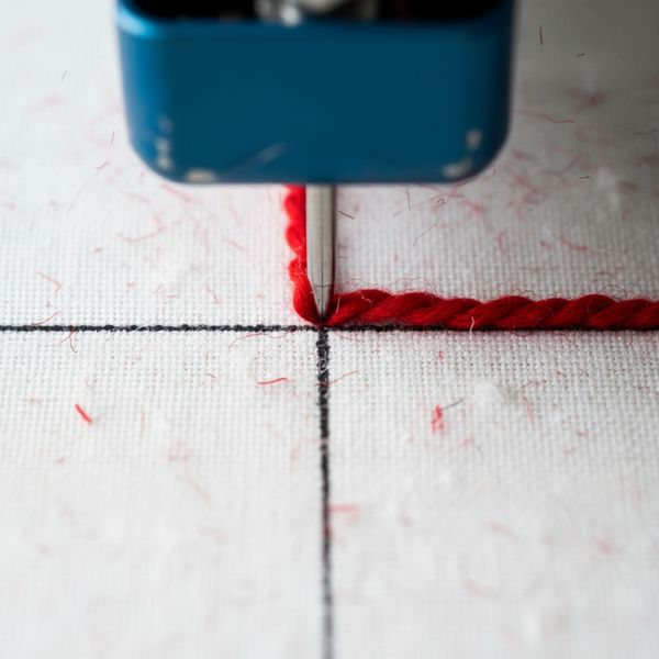 Close-up shot of a tufting gun's needle accurately following a drawn line on a tufting frame Close-up shot of a tufting gun's needle accurately following a drawn line on a tufting frame