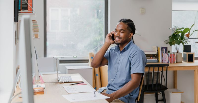 Man talks on cellphone at desk