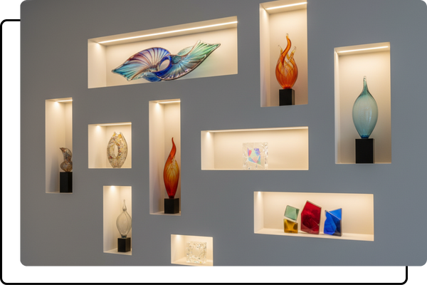 A gallery-style wall with multiple illuminated LED niches of various sizes, each showcasing a unique piece of colorful glass art.