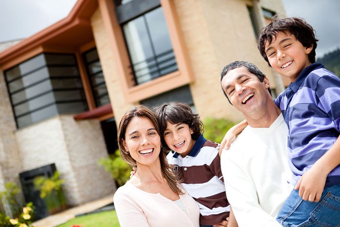 Family smiling outside house