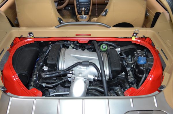 A detailed close-up view of a high-performance sports car engine with clean metallic components in a modern workshop.