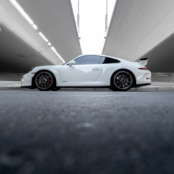 Technician performing a pre-track inspection and alignment check on a high-performance Porsche.