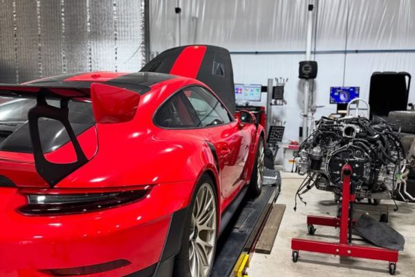 red Porsche GT2 inside of repair shop