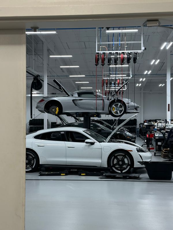 A technician uses specialized equipment to adjust the suspension components of a high-performance sports car on a digital alignment rack.