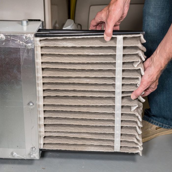 person replacing a furnace filter