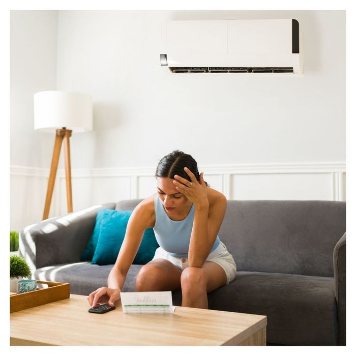 woman on couch looking at cooling bill