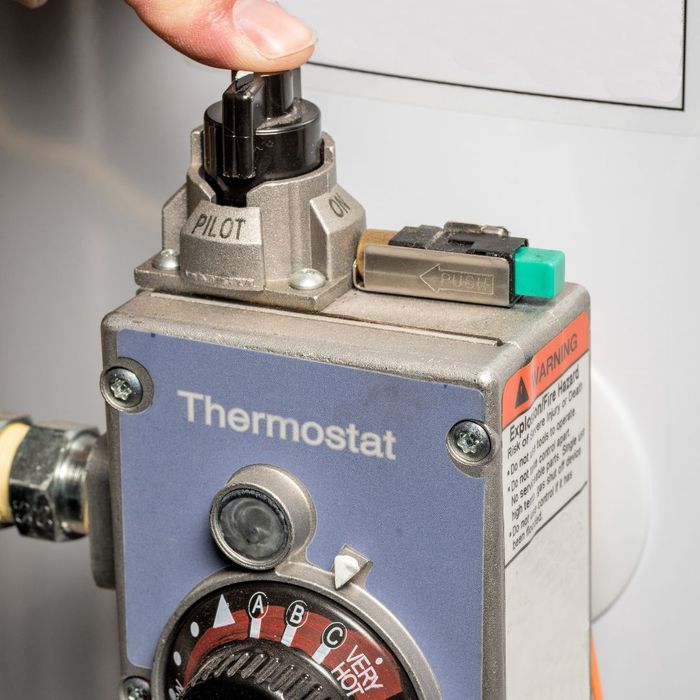 pressing the pilot light on a thermostat