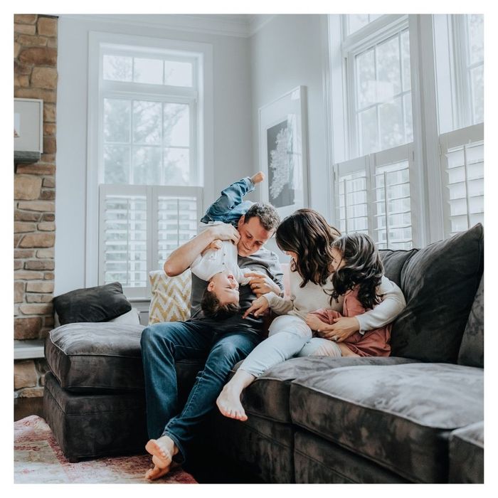 family with young kids laughing on couch