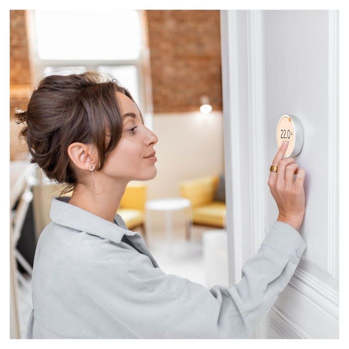 woman turning down thermostat