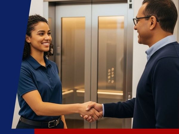 an elevator technician shaking hands with a satisfied client in front of their elevator