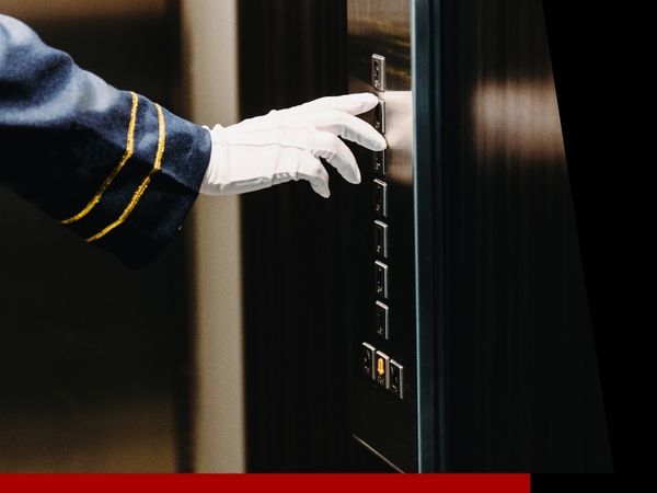 Gloved hand of employee press elevator floor buttons