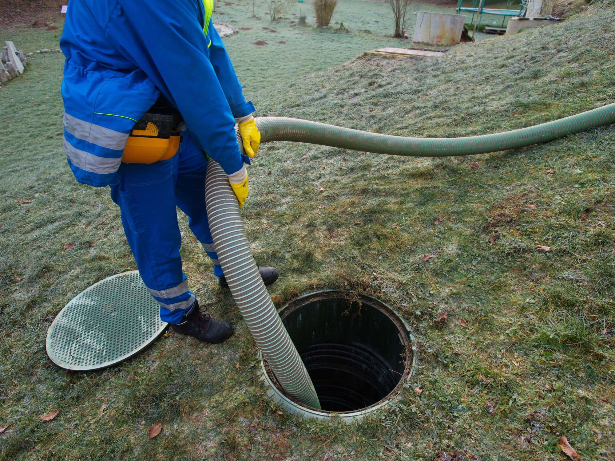 man holding hose going into septic hole