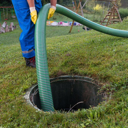 someone holds a tube into a septic tank hole