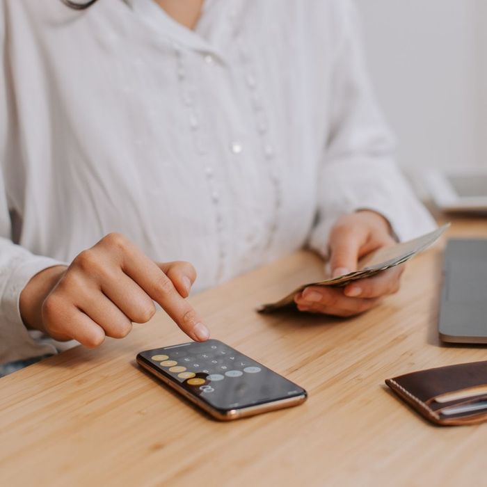 A close-up of a person using a calculator and reviewing financial paperwork on a desk.