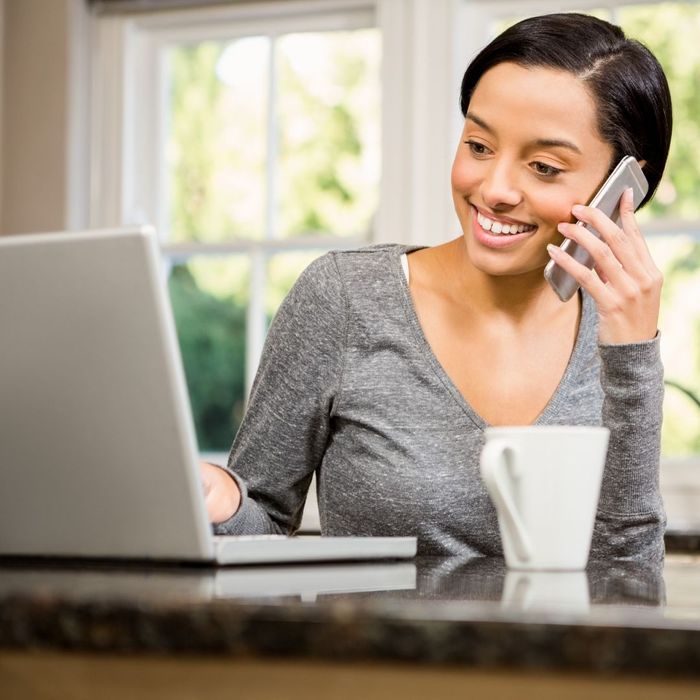 Person using a laptop while talking on the phone