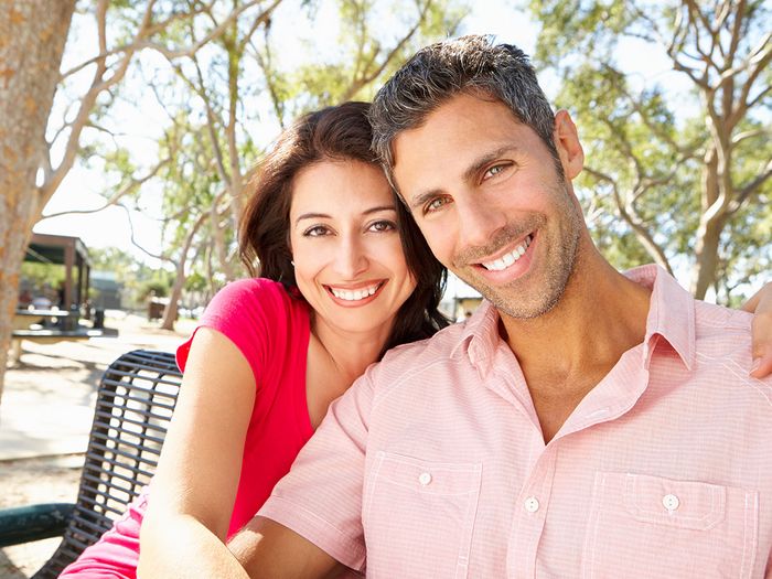 couple smiling while sitting on bench