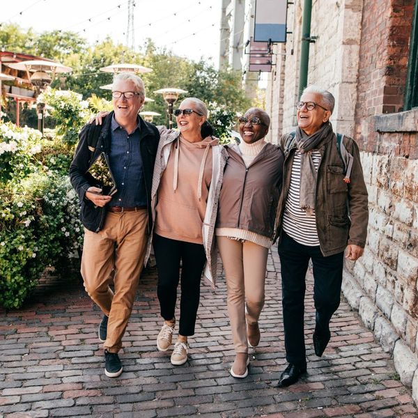 A group of retirees walk down a cobble stone path together on vacation