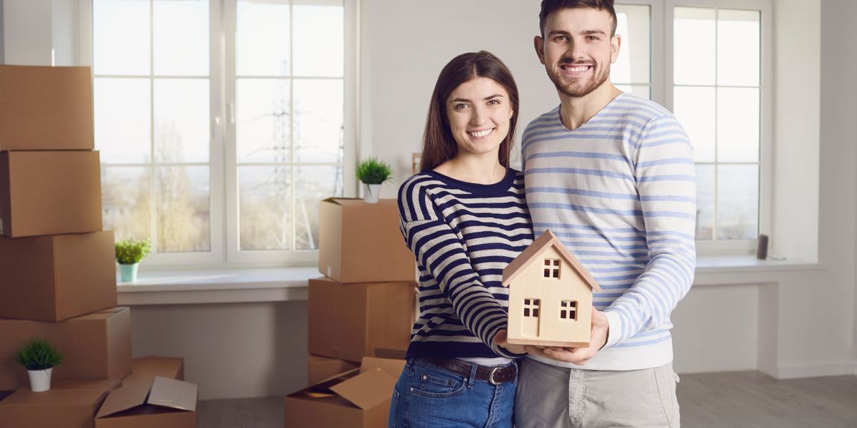 couple holding wooden house in new home