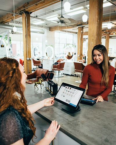 Two women in a local business running a payment on a tablet