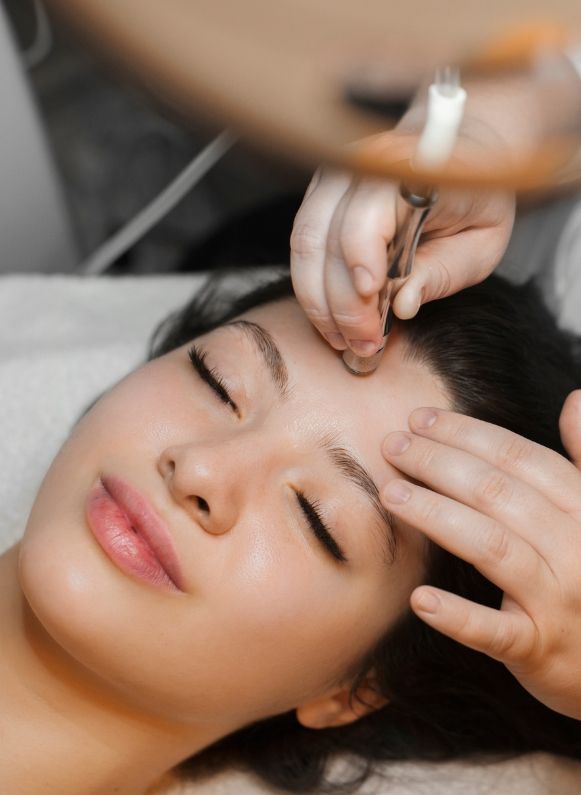 A woman relaxing while getting microneedling on her forehead