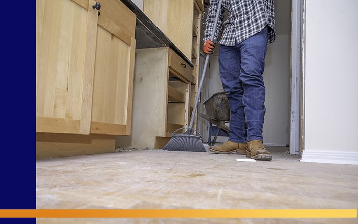 A man sweeping up a bathroom floor that's being remodeled