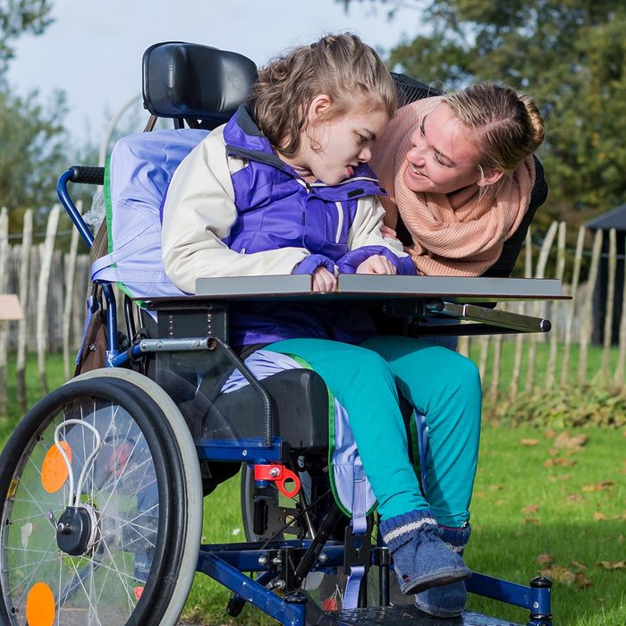 smiling woman talking to a girl with special needs in a wheelchair