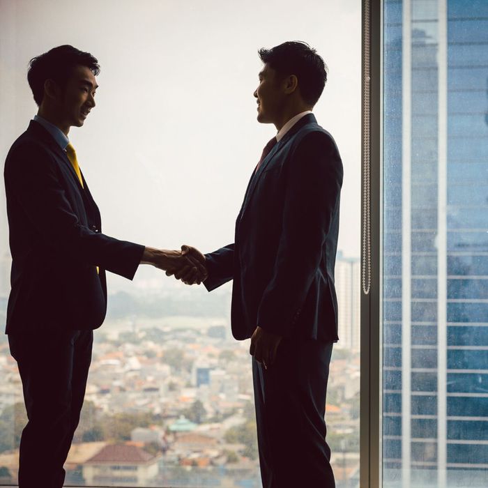 2 men shaking hands in tall building