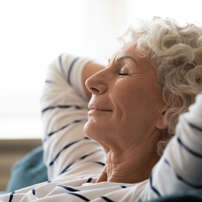 an older woman relaxing with her arms behind her head