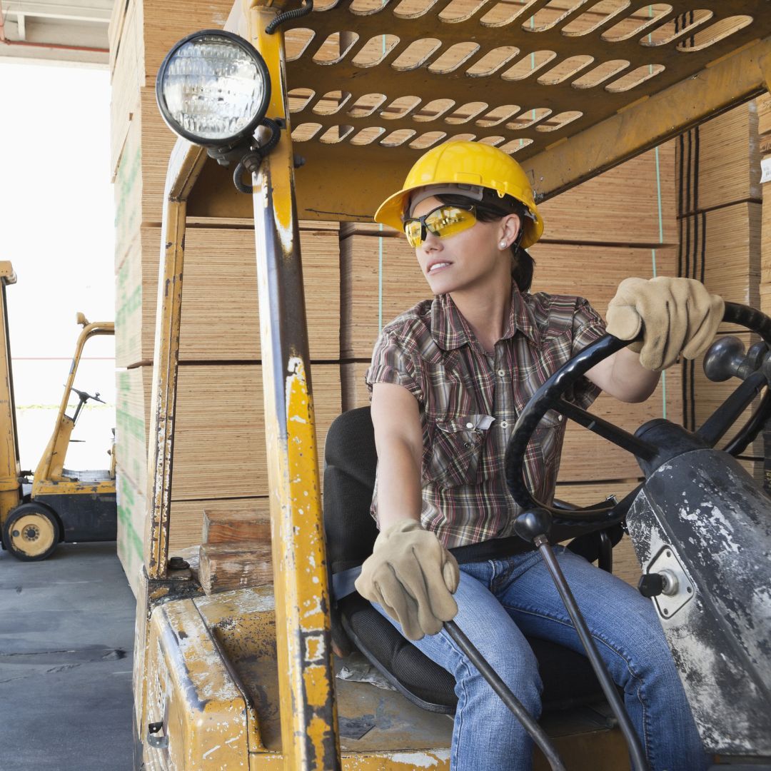 a woman working a forklift in a lumber yard